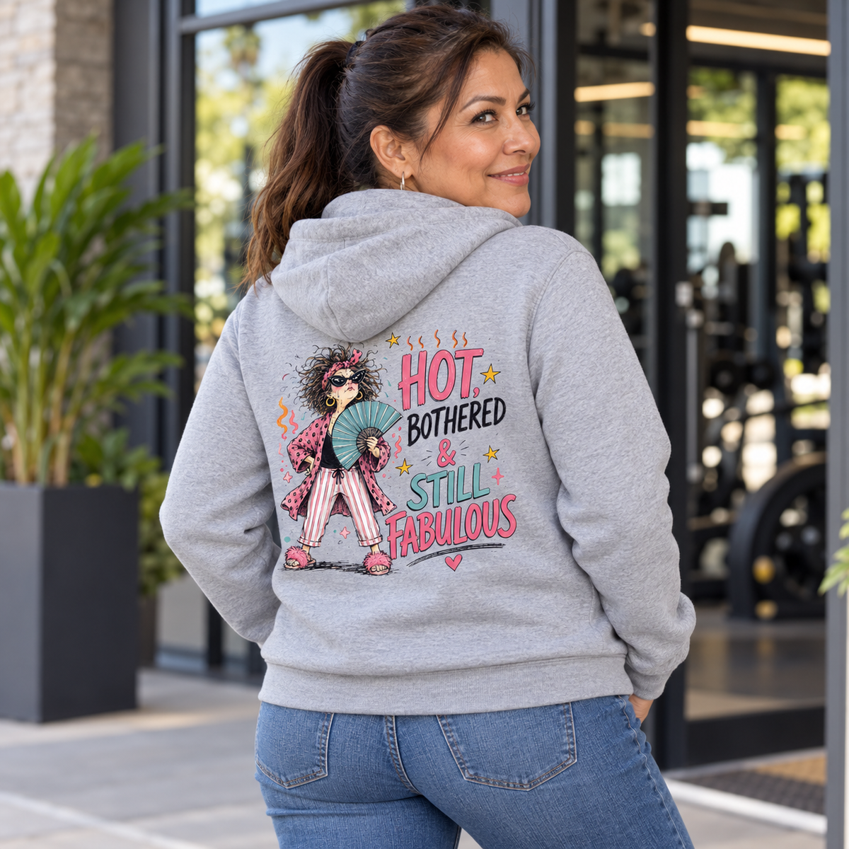 Latina woman in her 50s wearing the Hot Bothered and Still Fabulous grey hoodie, back view