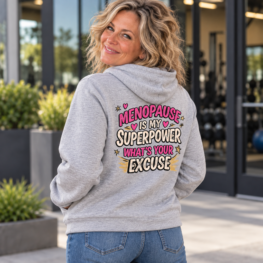Blonde woman in her 50s wearing the Menopause Is My Superpower grey hoodie, back view