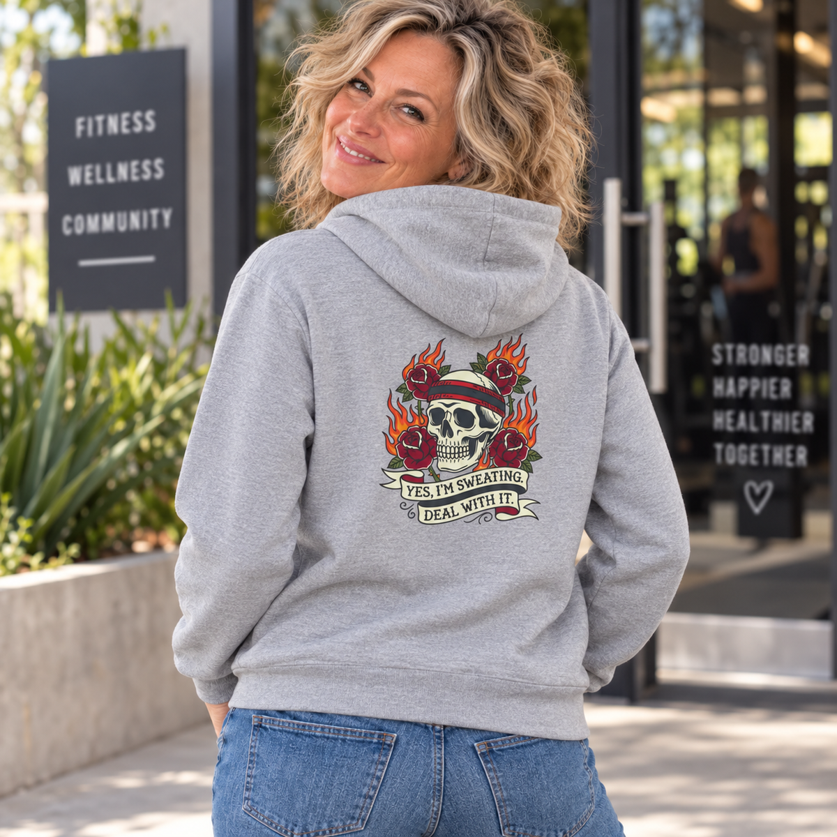 Blonde woman in her 50s modelling the Yes I'm Sweating Deal With It DTF back-print hoodie