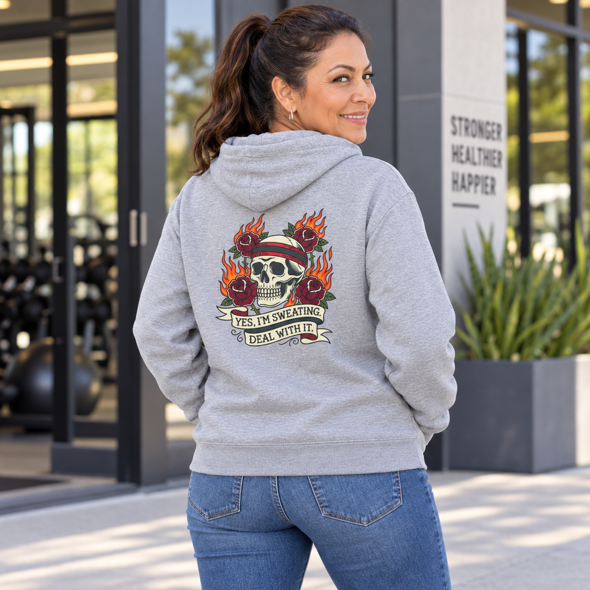 Latina woman in her 50s modelling the Yes I'm Sweating Deal With It DTF back-print hoodie
